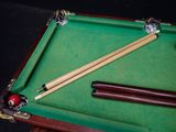 a pool table with two cues and a ball on it