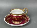 a red and gold cup and saucer on a saucer
