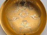 a gold spoon with a design on it on a white surface