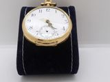 a small gold pocket watch on display on a white surface