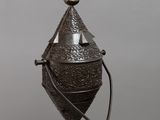 une vieille cloche en métal munie d'une poignée en bois et surmontée d'une croix