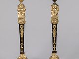 une paire de bougeoirs noirs et dorés ornés de figures