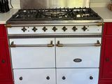 une cuisinière blanche et rouge dans une cuisine au sol en damier noir et blanc