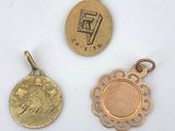 three small gold medallions and a coin on a white surface