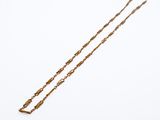 a gold necklace with a long chain on a white background
