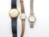 Deux montres et un bracelet de montre sont posés sur une surface blanche