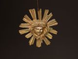 a gold ornament with a face of a person hanging from it