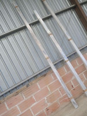 quatre poteaux métalliques adossés à un mur de briques