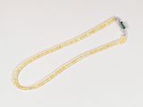 collier composé de perles jaunes et blanches, orné d'une fleur verte sur fond blanc