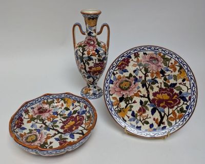 three plates and two vases sitting on a table