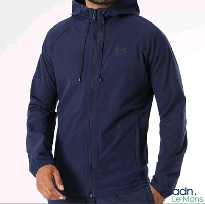 Un homme vêtu d'un sweat à capuche bleu se tient debout, les mains dans les poches.