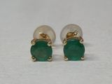 une photo d'une paire de boucles d'oreilles en émeraude posées sur une surface blanche