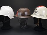 three hard hats on a mannequin head on a black background