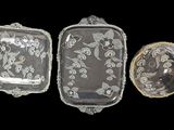 three pieces of glass with floral designs on them on a black background