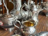 a table with silver teapots and silver spoons on it