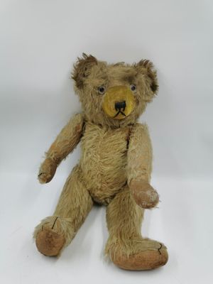 un ours en peluche marron assis sur une surface blanche