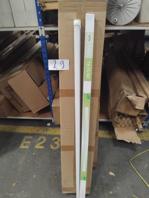 une pile de cartons et un tube blanc posés sur une étagère