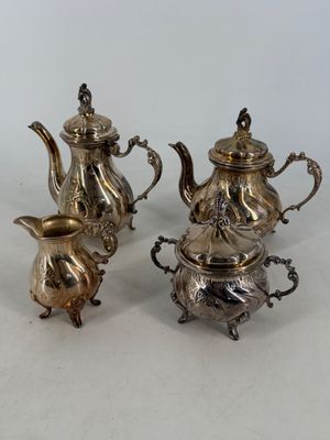 three pieces of silver tea and coffee set on a white surface