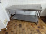 a stainless steel table with a shelf in the middle of a tiled floor