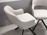two white chairs and a ottoman in a room with a wall