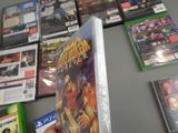 a person holding a video game in front of a wall of other video games