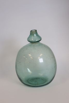 a green glass bottle sitting on a white surface