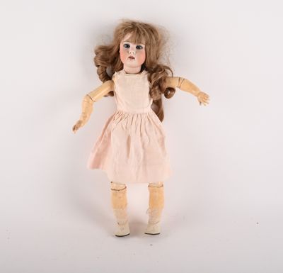 une vieille poupée aux cheveux longs, vêtue d'une robe, sur fond blanc