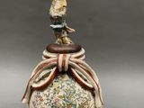 an image of a vase with a figurine sitting on top of it