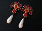 pair of red and white earrings with pearls on a black background
