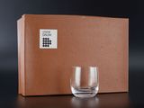a glass sitting in front of a box with a label on it