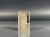 un vieux briquet posé sur une table près d'un mur gris