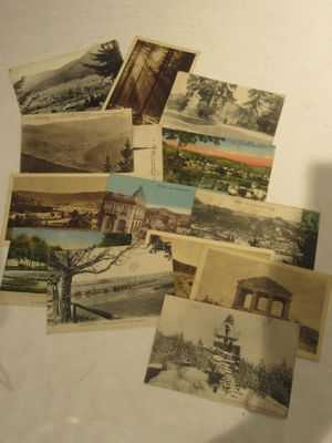 de nombreuses cartes postales anciennes posées sur une table, à côté d'une tasse de café