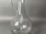 clear glass pitcher with a handle on a gray background
