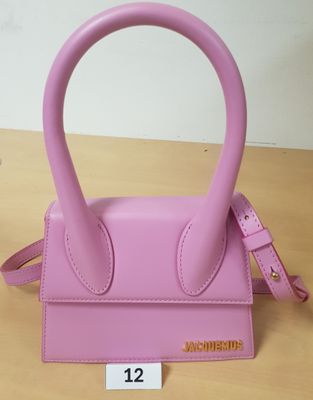 sac à main en cuir rose avec une poignée et une bandoulière, posé sur une table en bois