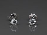 une paire de boucles d'oreilles en diamant posées sur une surface réfléchissante
