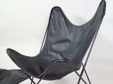 a black leather butterfly chair with a black foot rest
