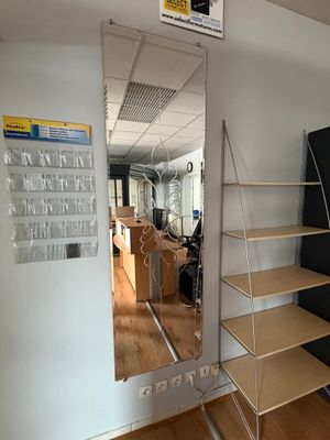 un miroir accroché au mur à côté d'une bibliothèque dans une pièce