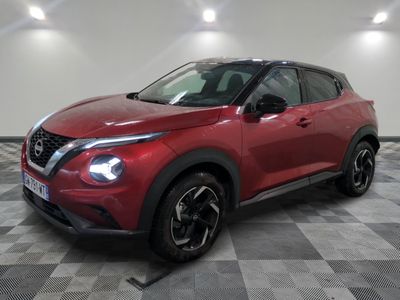 a red nissan suv parked on a checkered floor in a garage