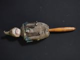 a small doll with a wooden handle on a black surface