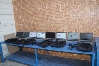 many laptops on a blue table in front of a brick wall