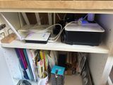 a computer and printer on a shelf in the corner of a room