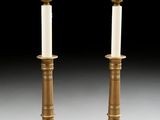 pair of antique brass candlesticks with white candles on them