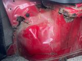 a red car that has been damaged and is sitting on the side of the road