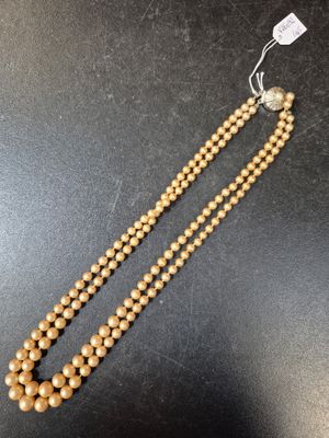 un gros plan d'un collier en perles de bois posé sur une surface noire