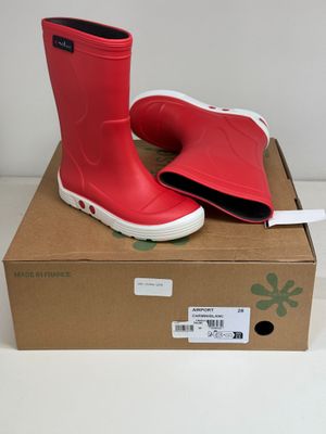 pair of red rain boots sitting on top of a cardboard box