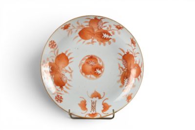 une assiette orange et blanche posée sur un support, sur une surface blanche