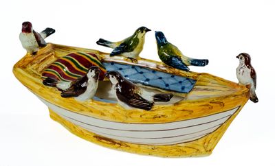 trois oiseaux perchés sur un petit bateau posé sur une surface blanche