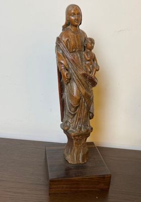 wooden statue of a woman holding a child on a table