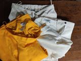 three pairs of yellow and white pants sitting on top of a wooden bench