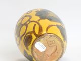 a yellow and black vase sitting on a white surface